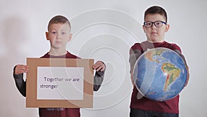 Boy holds a globe, a model of the planet Earth. Child is holding a sign with the inscription: TOGETHER WE ARE STRONGER