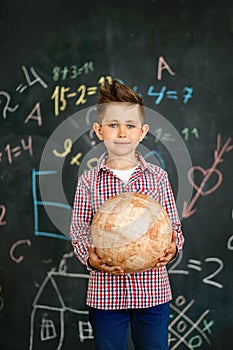 The boy holds the globe near the school board