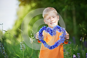 The boy holds in hand heart from flowers of a cornflower, soft f