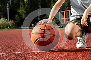 The boy holds in his hands a basketball closeup, against the background of a basketball court. The concept of a sports lifestyle,