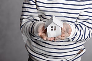 The boy holds in his hands the little white house. The concept of real estate, purchase, adoption.