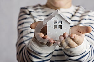 The boy holds in his hands the little white house. The concept of real estate, purchase, adoption. photo