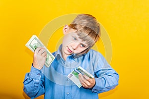 The boy holds in his hands the money banknotes dollars and euros, talking on the smartphone. The concept of success and financial
