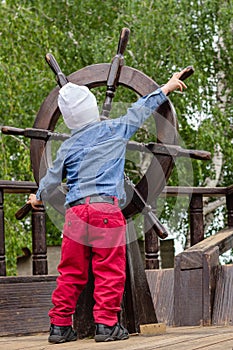 The boy holds a wooden ship`s wheel