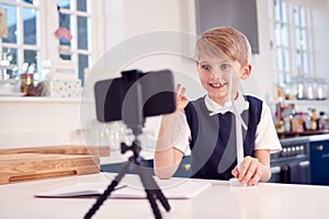 Boy At Home Wearing School Uniform With Model Of Wind Turbine Recording Video About Green Energy