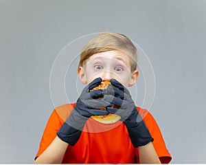 A boy with huge bulging eyes bites a burger