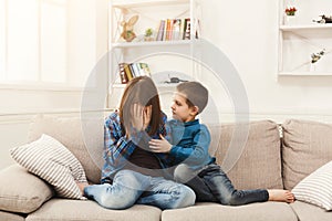 Boy hugging his crying sister at home