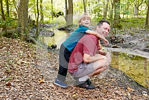 Boy hugging his father by a creek in the forrest