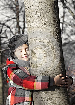 Boy hugging a tree, listening the sounds of the Nature.