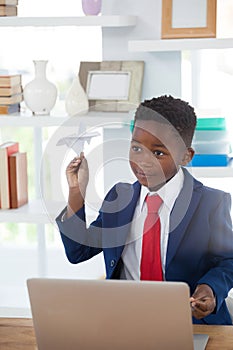 Boy imitating as businessman playing with paper airplane
