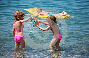 Boy on inflatable mattress in sea and girls nearby