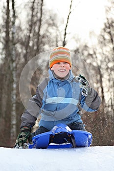 Boy intend drive from hill in winter on sledges