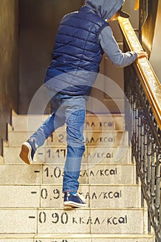 Boy in jeans and vest goes upstairs with calories marks