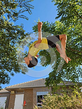 Boy jumping in the air on a background of green trees and blue sky