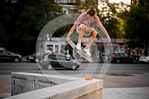 Boy jumping with the balance board in hand on the concrete border in the town