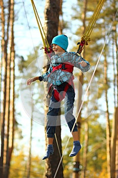 Boy jumping on a bungee trampoline and flying in the air in the autumn park