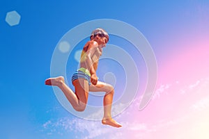 A boy is jumping from the cliff into the sea on a hot summer day. Holidays on the beach. The concept of active tourism