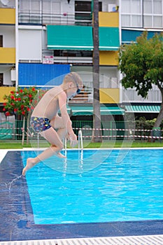 Boy jumping in cool water of swimming pool