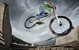 Boy jumping with his street-bike in the city.