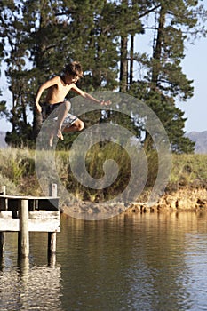 Boy Jumping From Jetty Into Lake