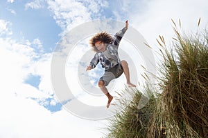 Boy jumping over dune