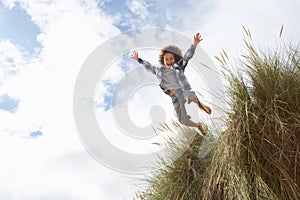 Boy jumping over dune