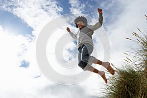 Boy jumping over dune