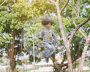 Boy jumping over the rope in the park on sunny summer day.