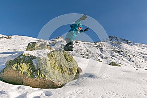 Boy jumping of a rock into snow