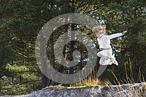 Boy jumping from sand dunes in pinewood forest