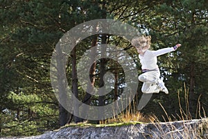 Boy jumping from sand dunes in pinewood forest photo