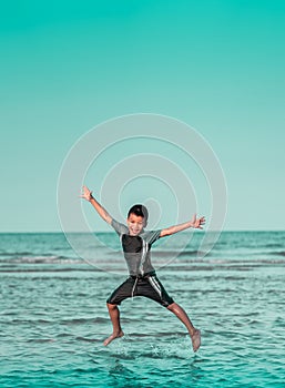 Boy is Jumping splashing water on a Beach for Children Summer Vacation happiness concept