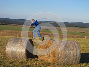 Boy jumping on the straw bales