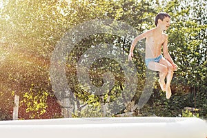 Boy jumping into the swimming pool in the garden at summer