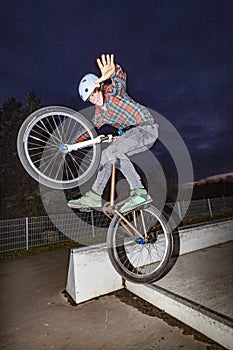 Boy jumps with his dirtbike in the skate park over a ramp