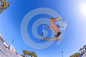 Boy jumps with his scooter at a skate park