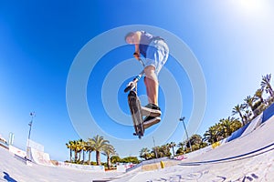 Boy jumps with his scooter at a skate park