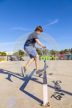 Boy jumps with his scooter at a skate park