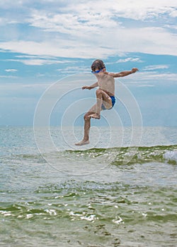 Boy jumps on sea above water. child jumps into water. Boy in air above sea. Holidays in summer