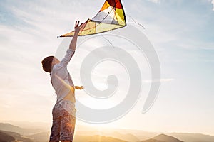 Boy jumps and strats to fly a kite in the sky