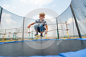 The boy jumps on a trampoline in an amusement park, performing various stunts