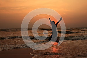 A boy jumps in the waves during sunset