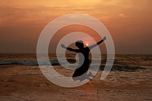 A boy jumps in the waves during sunset