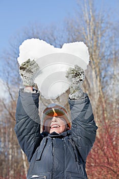 Boy keeps in hands hearts from snow over head photo