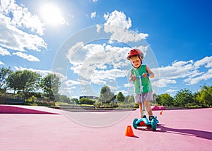 Boy on the kick scooter ride around orange cones at skate park