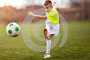 Boy kicking football on the sports field