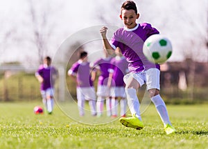 Boy kicking football on the sports field