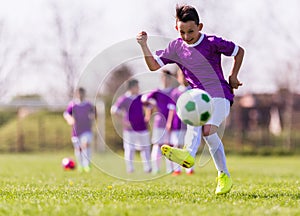 Boy kicking football on the sports field