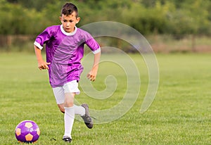 Boy kicking football on the sports field