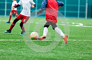 Boy is kicking soccer ball. Boy is running after the ball on green grass. footballer in white and red shirt. boys dribbling.